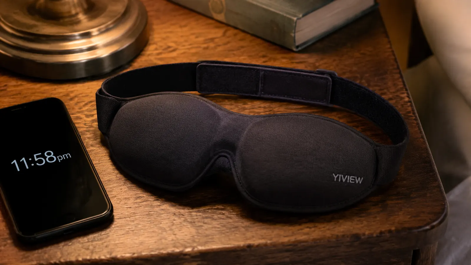 Close-up of the YIVIEW sleep mask's contoured eye cups and adjustable strap laid flat on a nightstand